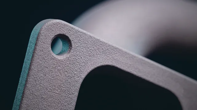 Close-up render of the manifold flange corner as printed, with a fine open powder grain around a bolt hole.