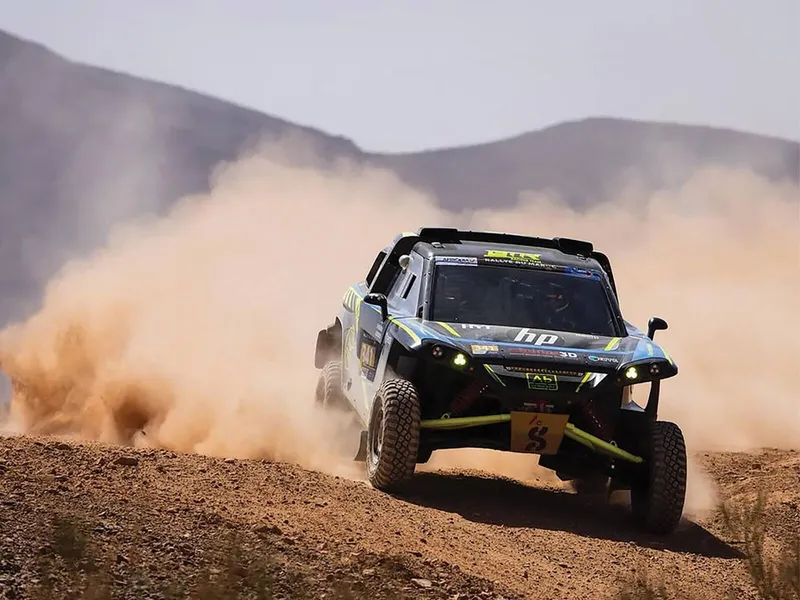 ABConcept rally car throwing up a plume of dust on a desert stage