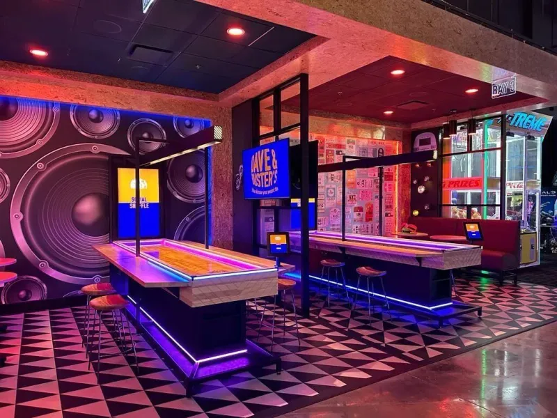 Digital shuffleboard tables lit in neon colors in a bar
