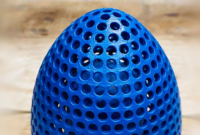 Blue 3D-printed strainer with a perforated, egg-shaped body