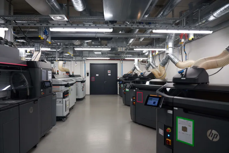 Protolabs production floor: a row of HP Multi Jet Fusion printers under extraction ducts