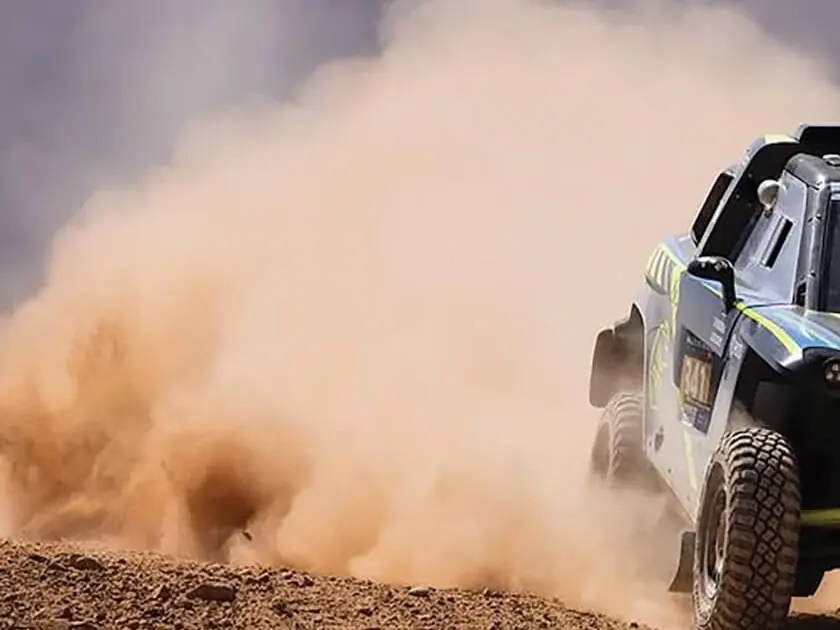ABConcept rally car throwing up a plume of dust on a desert stage