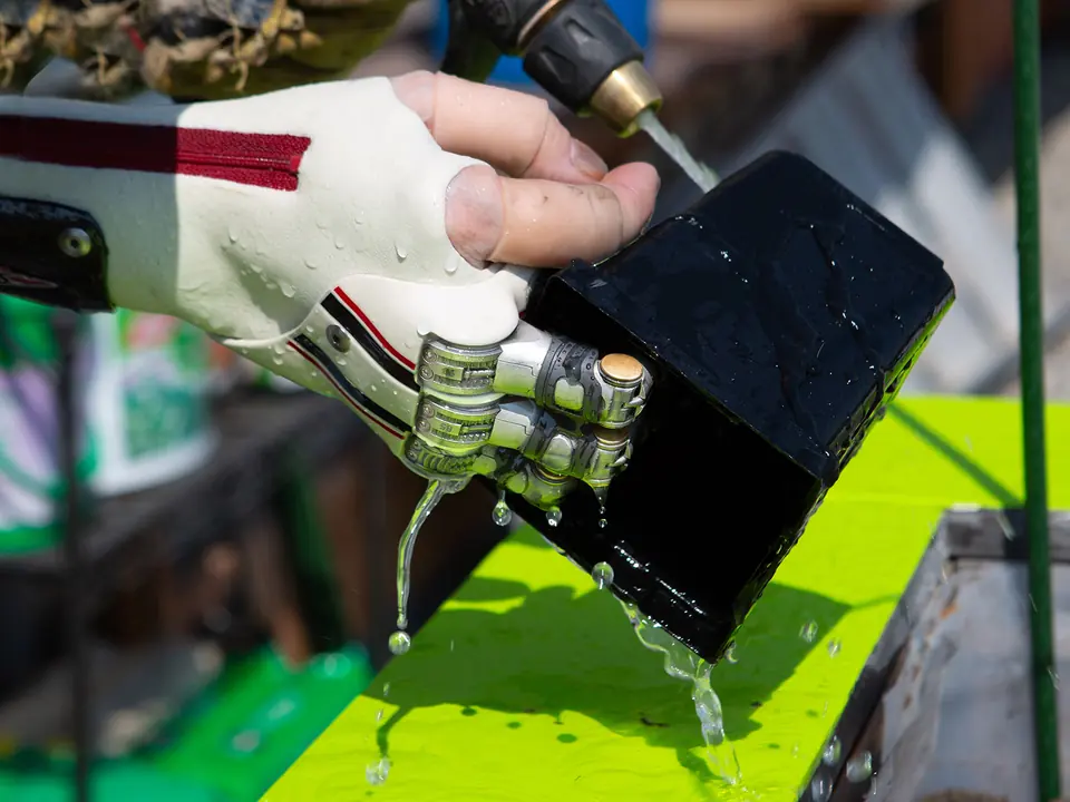 A partial hand prosthesis gripping a box under running water